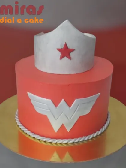 A powerful and bold Wonder Woman cake. This design features her iconic 'W' emblem and a tiara topper, all in vibrant red, silver, and gold, perfect for celebrating the superhero in your life.