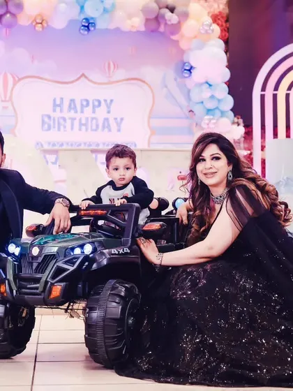 The birthday boy with his parents and his new toy jeep at his party.