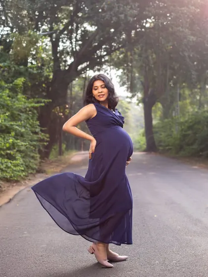 A beautiful portrait of the mom-to-be on a tree-lined road, the flowing blue dress adding a touch of elegance to the natural setting.