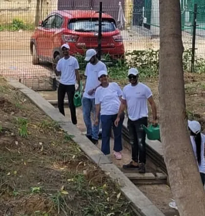Volunteers from Orbis Financial carry watering cans along a path at Aravali Creek, ready to nurture the new saplings they've planted.