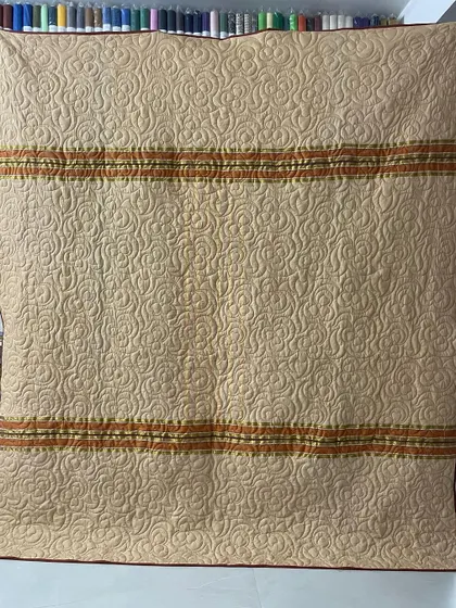 The reverse side of a saree quilt, showcasing a neutral tone that makes the intricate quilting pattern stand out.