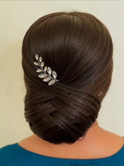 A classic French twist bun, also known as a chignon, with a simple crystal leaf pin. This is the epitome of timeless elegance and sophistication.