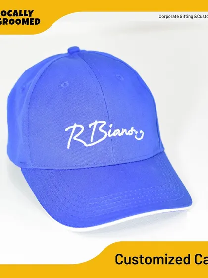 A clean shot of a royal blue customized cap with a simple and elegant white embroidered logo for 'R Biano'. This is a great example of a classic branded cap for corporate use.