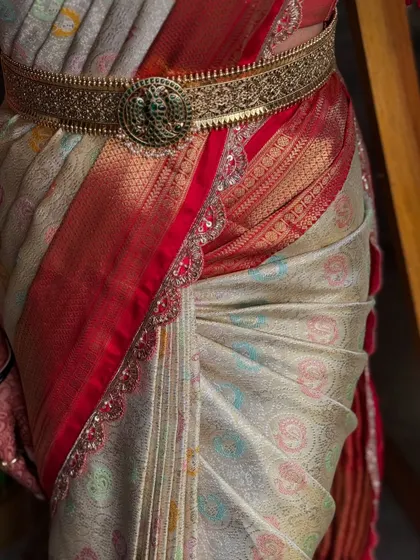 A close-up on the waist, showing the perfect drape and the beautiful detail of the vaddanam. These are the finishing touches that complete the bridal look.