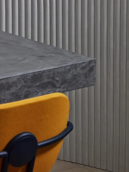 A close-up of the 'Pilastre' 3D wallcovering, showing its velvety, architectural texture. The play of light and shadow on the fluted surface adds depth and sophistication.