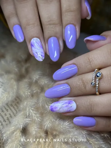 An elegant set featuring lilac polish with beautiful purple and white marble accents. This is a perfect combo for clients who want a stylish and artistic design.