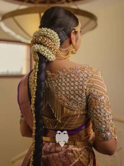The back view of Priya's reception look, showing the detailed embroidery and beautiful hair adornments.