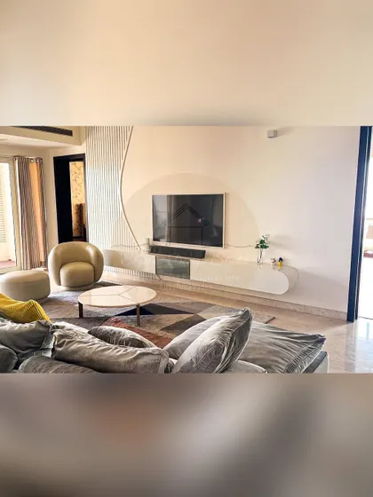 The family living area in our Prestige White Meadows project. This space features a comfortable grey sectional sofa and a unique, minimalist TV wall with curved, textured details for a touch of modern elegance.