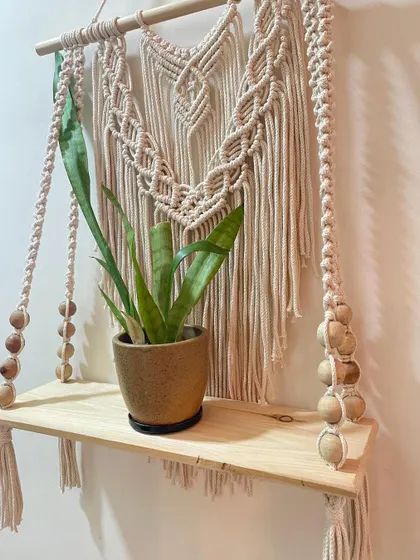 Another view of the macrame floating shelf, showing how the detailed knot work supports the sturdy wooden plank. It's a perfect piece for displaying your treasures.