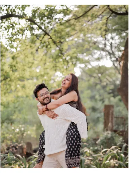 The groom gives his fiancée a piggyback ride during their pre-wedding shoot, a moment filled with genuine laughter and joy.