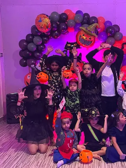 Our little monsters, witches, and superheroes posing for a group photo at the Halloween party. The decorations and spooky lighting really set the mood for a fun time.