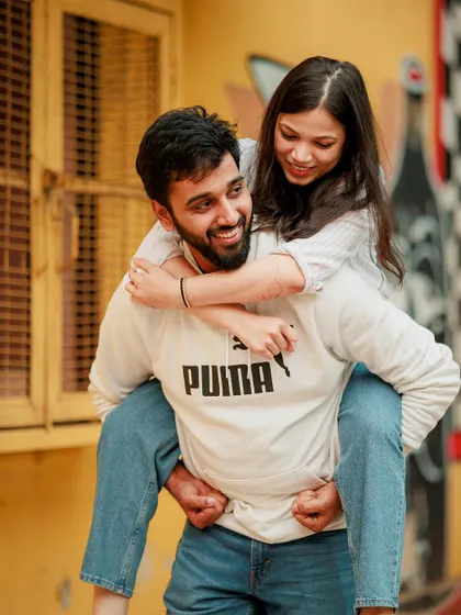 Love should be fun. This playful piggyback ride against a vibrant city backdrop in Delhi shows the joyful, carefree side of your relationship. We believe in capturing the real laughter and candid interactions that make your bond unique.