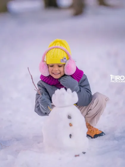 A close-up of my daughter adding the final touches to her snowman. These small, focused moments are just as important as the big family portraits.