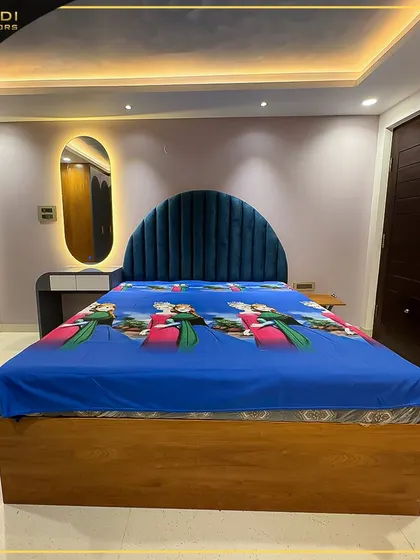A child's bedroom featuring a vibrant blue velvet arched headboard and a bed with a fun, themed bedspread. The room includes a modern vanity with a backlit mirror.