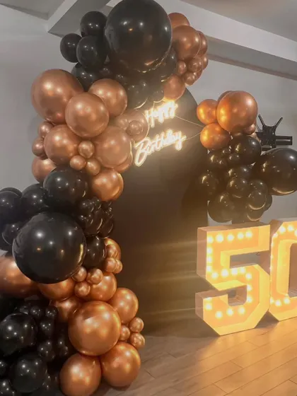 A straight-on shot showcasing the complete 50th birthday setup. The balance between the glowing numbers, the neon sign, and the balloon arrangement creates a visually appealing and photo-ready scene.