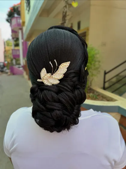 A beautifully structured braided bun, finished with a sparkling butterfly accessory. This is a clean, polished updo perfect for a formal event.