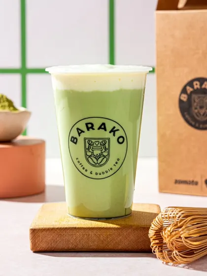 A matcha cheese foam tea from Barako. The styling includes a bamboo whisk to emphasize the authentic matcha ingredient.