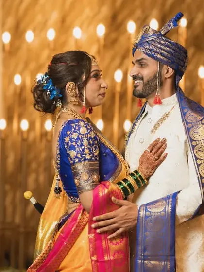 A classic pose against a backdrop of warm lights, showcasing the couple's stunning traditional Maharashtrian wedding attire.