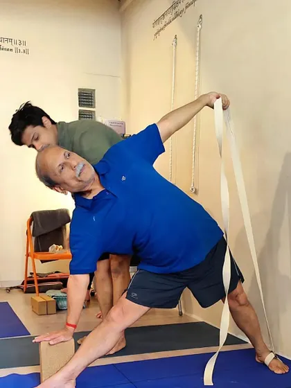 At Yoga Shala Arles in the South of France, using the wall ropes to refine Trikonasana. The shala's walls are inscribed with sutras, creating a sacred space for practice.