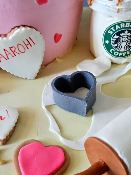 A detail from the baker-themed cake, showing the edible heart-shaped cookies, a fondant heart cutter, and a rolling pin in action.