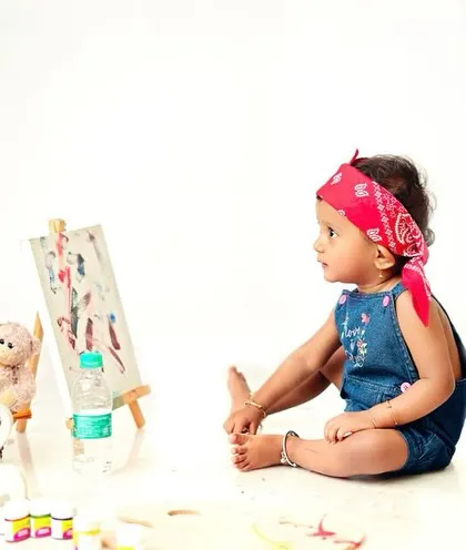 This little artist is taking a moment to admire her work. The red bandana adds a pop of color and personality to the shot.