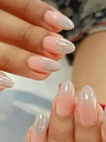 A soft and shimmery ombre look, blending a natural pink base with a pearlescent, glittery tip.