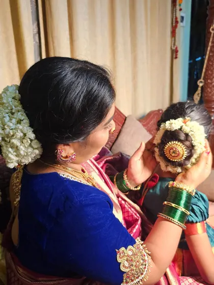 A beautiful moment between a mother and daughter, both adorned with traditional hairstyles featuring jasmine flowers. This captures the passing down of our cultural traditions.