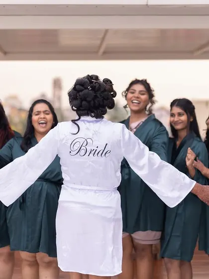 A fun and candid moment between the bride and her bridesmaids, all in matching robes, sharing a laugh before the ceremony.