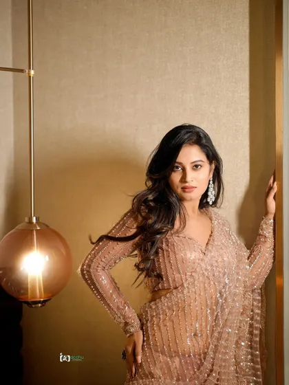 A more direct and confident pose from the same series. The lighting highlights the intricate beadwork of the saree, adding a touch of glamour.
