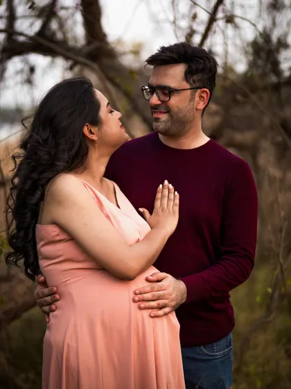 An expecting couple shares an intimate gaze in a natural, outdoor setting. This candid moment captures the deep connection and anticipation between partners during pregnancy.