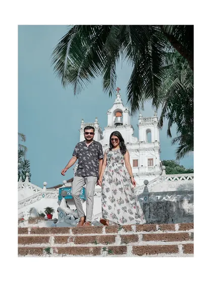 A classic Goa pre-wedding shot with the couple walking down the steps of a picturesque white church, capturing the iconic architecture of the region.