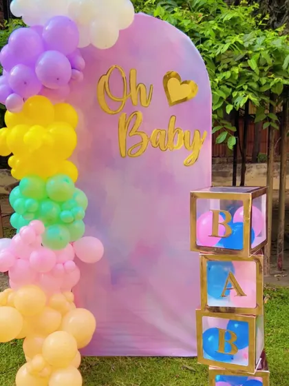 A lovely pastel-themed setup for a pre-delivery or maternity photoshoot. The "Oh Baby" sign, rainbow balloon pillar, and 'BABY' blocks create a perfect backdrop.