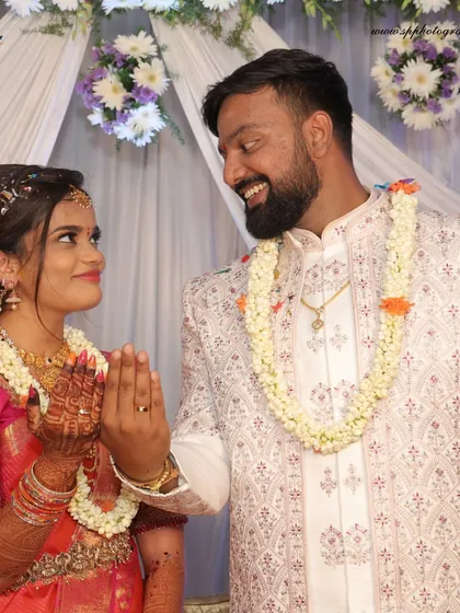 A sweet, candid moment from an engagement ceremony. The bride's 'namaste' gesture and the couple's shared smile create a warm and welcoming photograph.