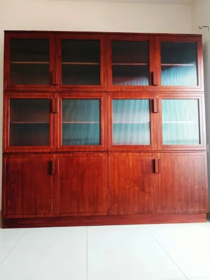 A mighty, handcrafted bookshelf with fluted glass and solid wood doors. This bespoke piece is a book lover's delight, offering enormous storage capacity with a classic, elegant look.