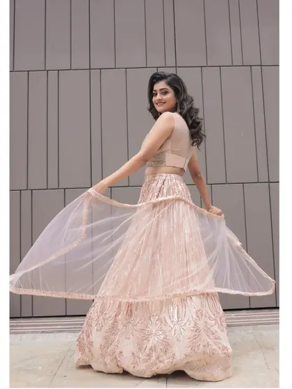 A playful, twirling shot in our peach sequin lehenga. This outfit is a great modern take on traditional wear, perfect for receptions or parties.