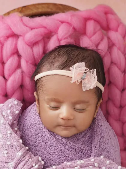 Pretty in pink and purple. This close-up of a sleeping newborn girl shows how I use color to create a soft and sweet mood, with a chunky pink knit blanket and a lavender wrap.