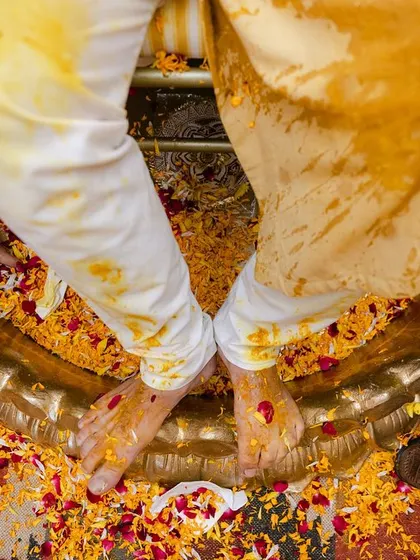 The aftermath of a joyful Haldi ceremony, with feet covered in turmeric and marigold petals. This image captures the pure, uninhibited spirit of the celebration.