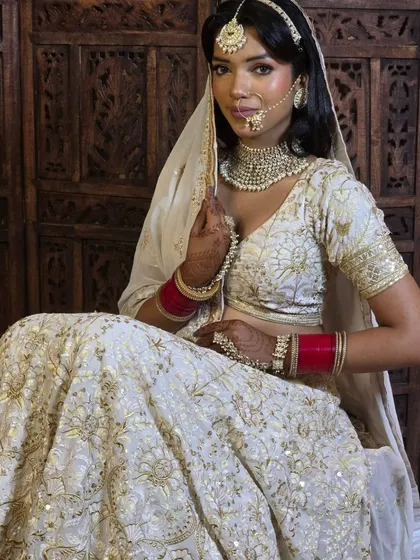 An elegant and timeless look. This bride is wearing a simple but stunning Polki choker set with a matching maang tikka and nath, perfect for her white and gold lehenga.