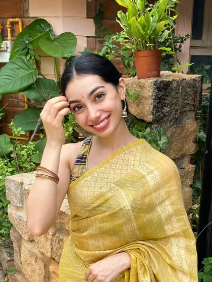 A happy, festive look in a beautiful yellow saree. This candid-style photo is great for social media content, capturing the genuine joy and spirit of the festive season.