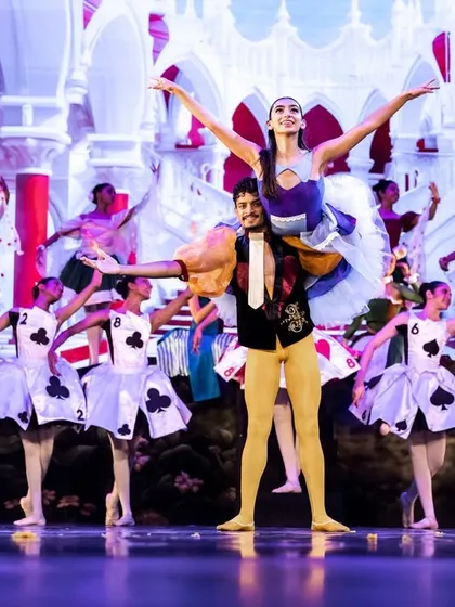 A principal lift from "Alice," featuring our lead dancers surrounded by the card ensemble. We train our dancers in pas de deux (partnering) techniques essential for classical ballet storytelling.