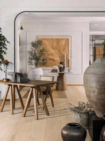 Layering is key to creating depth. This vignette shows how we built the space: a wooden floor panel on the wall as a backdrop, a trestle desk as the centerpiece, and curated urns and artifacts to add texture and personality.