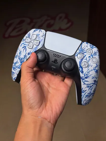 The finished "Qinghua" inspired PS5 controller, held up to show the intricate, hand-painted blue floral design.