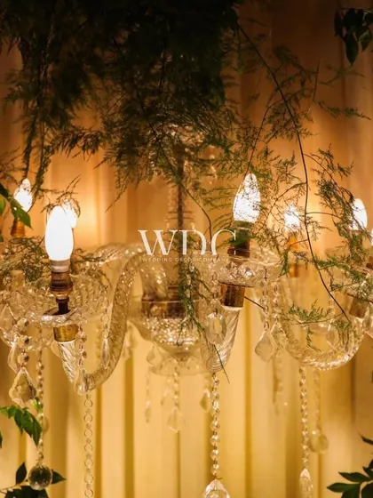 A close-up of a crystal chandelier, with delicate greenery woven through it. This detail adds a touch of natural beauty to the vintage and regal theme.