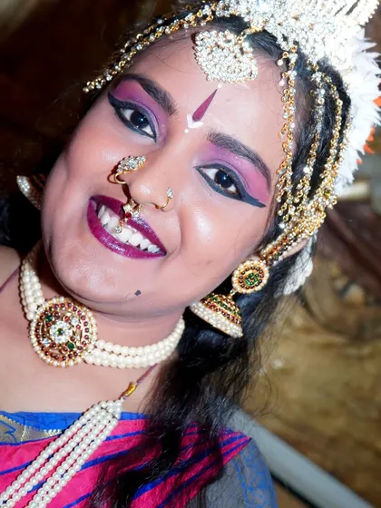 A close-up portrait capturing the dancer's joyful expression and the intricate details of her headpiece and makeup.