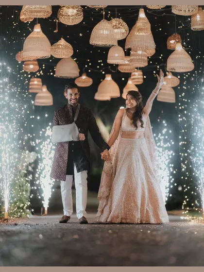 Let the celebrations begin. We love creating picture-perfect moments like this grand entry, framed by a canopy of wicker lamps and sparkling cold pyros, making the couple feel like the main characters of their love story.