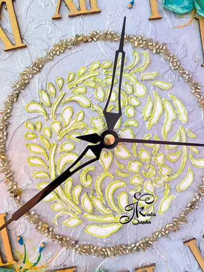 A close-up of the clock's center, featuring a delicate yellow stencil pattern.
