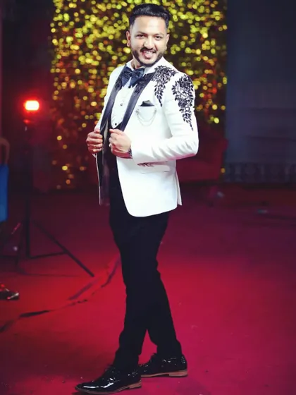 A full-length view of our handcrafted white tuxedo on a happy client. The tailored black trousers and polished shoes complete this sophisticated look for any high-profile wedding or reception.