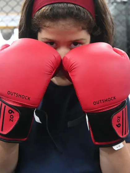 A close-up of one of our young female students, ready to train with her boxing gloves. She has the focus and determination of a future champion.