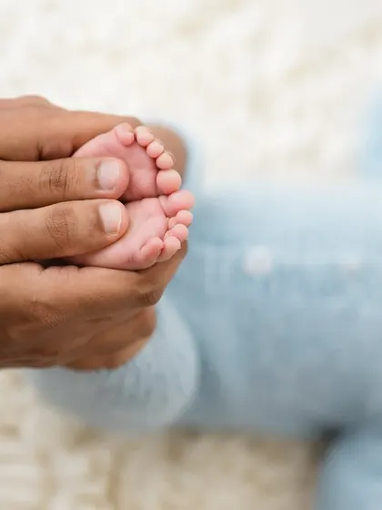 A father's hands gently massaging his baby's feet. A simple, loving moment captured in time.