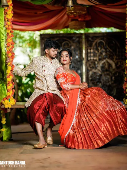 A regal portrait of a couple in traditional attire posing on a decorated swing.